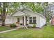 Charming one-story home features a quaint porch with swing, landscaped yard, and pink front door at 6142 Evanston Ave, Indianapolis, IN 46220
