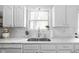 Bright kitchen features white cabinets, subway tile backsplash, and stainless steel sink under window at 6142 Evanston Ave, Indianapolis, IN 46220