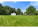 Green yard on a sunny day with a large barn style building and a single Gathering home at 6208 S 200 W, Trafalgar, IN 46181