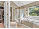 Bright bathroom features a glass-enclosed shower and a separate soaking tub with a window at 6374 Timberbluff Cir, Avon, IN 46123