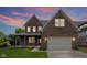 Beautiful two-story brick home with a covered front porch, an attached two-car garage, and well-manicured lawn at sunset at 6553 Stone Pointe Way, Indianapolis, IN 46237