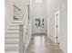 Bright foyer featuring wood-look floors, white stairs, and a front door with sidelights bringing in natural light at 6553 Stone Pointe Way, Indianapolis, IN 46237