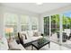 Bright sunroom with white sofas, large windows, and sliding glass doors leading to the outdoor deck at 6570 Freemont Ln, Carmel, IN 46033