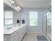 Bright bathroom features a double sink vanity, a glass-enclosed shower, and natural light from a window at 6664 Kara Ln, Brownsburg, IN 46112