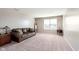 Comfortable living room features a leather sofa, plush carpet, and natural light from a window at 6664 Kara Ln, Brownsburg, IN 46112