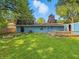 Back of the house with a large green lawn, mature trees, and a wooden deck at 6739 Westdrum Rd, Indianapolis, IN 46241