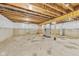 Unfinished basement with concrete floor, utility hookups, and exposed wooden ceiling joists offers potential for customization at 7604 Brownstone Ct, Greenfield, IN 46140