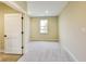 Neutral-toned bedroom with soft carpet, a window offering outdoor views, and a closed door at 7604 Brownstone Ct, Greenfield, IN 46140