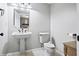 Bright white bathroom with a pedestal sink, modern toilet, light tile floor, and small window at 7702 N County Road 300 W, Lizton, IN 46149