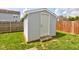 Backyard shot of detached storage shed, green grass, wood fencing, and a concrete entrance at 9593 W Constellation Dr, Pendleton, IN 46064