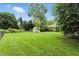 Large backyard with mature trees, garden shed, chain link fence, and patio at 1013 Chapman Blvd, Greenfield, IN 46140