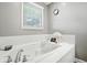 Close-up of a large soaking bathtub with a window and white tile surround in the bathroom at 1013 Chapman Blvd, Greenfield, IN 46140
