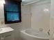 Bathroom featuring a bathtub with white tile surround, modern fixtures, and a vanity area at 106 N 300 W, Greenfield, IN 46140
