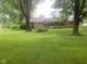 Charming single-story brick home on a lush, green lawn with mature trees providing shade at 106 N 300 W, Greenfield, IN 46140