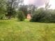 View of the grassy lot with a shed surrounded by mature trees and landscaping at 106 N 300 W, Greenfield, IN 46140