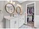 Bathroom featuring double sinks, white cabinets, stylish mirrors, and a walk-in closet at 11123 Garrick St, Fishers, IN 46038