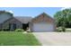 Beautiful brick house with an attached two-car garage, complemented by a green lawn and mature trees at 126 Old Farm Rd, Danville, IN 46122