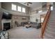 Open living room with high ceilings, a fireplace, a gray sectional sofa, and access to a wooden staircase at 13884 Wendessa Dr, Fishers, IN 46038