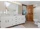Modern bathroom with dual sinks, marble countertop, shower, and wood paneled door at 1393 Stoney Creek Cir, Carmel, IN 46032