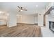Open-concept living room with wood-look flooring, a ceiling fan, and white brick fireplace at 1540 Roanoke Dr, Zionsville, IN 46077