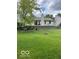 Spacious backyard with lush green grass, a retaining wall, mature trees, and a charming firepit at 17717 Cedarbrook Dr, Westfield, IN 46074
