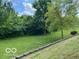 Picturesque backyard featuring a retaining wall, mature trees and lush greenery perfect for outdoor enjoyment at 17717 Cedarbrook Dr, Westfield, IN 46074