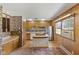 Well-lit kitchen with an island cooktop, stainless steel refrigerator, and wood-paneled walls at 1841 Shady Ln, Martinsville, IN 46151