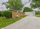Brick home with gravel driveway and a metal shed, offering a combination of residential and storage space at 203 Plum E St, Frankton, IN 46044