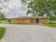 A brick home exterior with a gravel parking and large trees, providing a peaceful and private setting at 203 Plum E St, Frankton, IN 46044