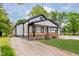 Beautiful home with black trim and a covered porch, surrounded by green grass and gravel driveway at 2125 N Pasadena St, Indianapolis, IN 46219