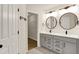 Modern bathroom with a double sink vanity, round mirrors, stylish lighting fixtures, and a door leading to a walk-in closet at 214 Handley St, Indianapolis, IN 46222
