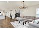Bright living room featuring hardwood floors, a modern chandelier, comfortable seating, and seamless access to the kitchen at 214 Handley St, Indianapolis, IN 46222