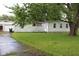 Exterior view of a home with white siding, surrounded by lush greenery and a mature tree at 220 S 2Nd St, Summitville, IN 46070