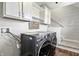 Laundry room featuring gray front load machines and white cabinets next to carpeted stairs at 2308 E Mill Stream Dr, Greenfield, IN 46140