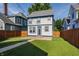 The backyard features a lush green lawn, a concrete walkway, string lights, and a well-maintained wooden fence at 2347 N Pennsylvania St, Indianapolis, IN 46205