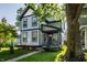 Charming two-story home features blue and grey siding, covered porch, well-kept landscaping, and mature trees at 2347 N Pennsylvania St, Indianapolis, IN 46205
