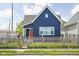 Charming blue home featuring a well-manicured lawn, a picket fence and a bright orange front door at 413 E Caven St, Indianapolis, IN 46225