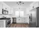 Bright kitchen featuring stainless steel appliances, white cabinets, and a stylish backsplash at 413 E Caven St, Indianapolis, IN 46225