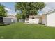 The backyard features a lush lawn and mature trees, a detached garage, and additional outbuilding at 5134 Rinehart Ave, Indianapolis, IN 46241