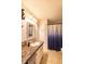 Cozy bathroom with a single sink, marble countertop, and storage cabinets adjacent to a shower with a blue curtain at 5387 E County Road 800 S, Mooresville, IN 46158