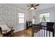 Bedroom with hardwood floors, two windows, a rocking chair, and charming wallpaper at 5715 Oak Ave, Indianapolis, IN 46219