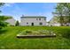 Well-manicured backyard featuring garden beds, a fire pit, and a home with neutral vinyl siding at 6848 Harriet Dr, Indianapolis, IN 46237