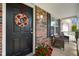 Elegant front door with a decorative wreath, accented by a brick facade and potted flowers at 6848 Harriet Dr, Indianapolis, IN 46237
