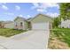 Charming one-story home with green siding, red brick accents, and a wide driveway leading to a two-car garage at 8355 Fieldfare Way, Indianapolis, IN 46237