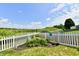 Scenic backyard featuring a white picket fence, lush garden, and a tranquil pond view at 9022 Hosta Way, Camby, IN 46113