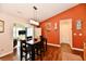 Inviting dining area featuring a hardwood floor, a unique orange accent wall, and natural lighting at 9022 Hosta Way, Camby, IN 46113