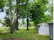 Spacious backyard with mature trees, lawn, and outbuildings at 94 N Routiers Ave, Indianapolis, IN 46219