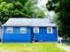 Charming blue home with a well-maintained lawn and mature trees surrounding the property at 94 N Routiers Ave, Indianapolis, IN 46219