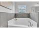 Bathroom featuring a large soaking tub with marble tile surround and white trim at 9724 Brooks Dr, Fishers, IN 46055