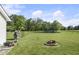 Picture of a cozy backyard with a firepit, wood pile and a pond surrounded by lush greenery at 1016 W Creek Ridge Dr, Fountaintown, IN 46130
